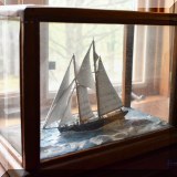 D73. Model ship in glass box.
